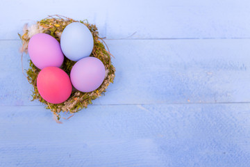 Colorful Easter eggs on a wooden board with feathers