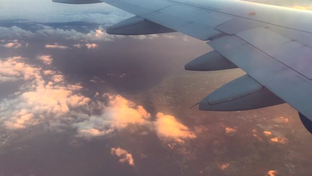Airplane flight. Wing of an airplane flying above the clouds with sunset sky. View from the window of the plane. Aircraft. Traveling by air. 4K UHD video footage. Ultra high definition 3840X2160