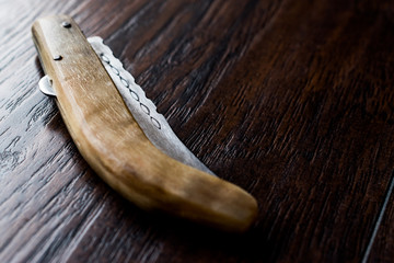 Handmade Wooden Pocket Knife on Dark Surface.