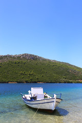 Fototapeta na wymiar fishing boat on the background of the green mountain sithonia greece