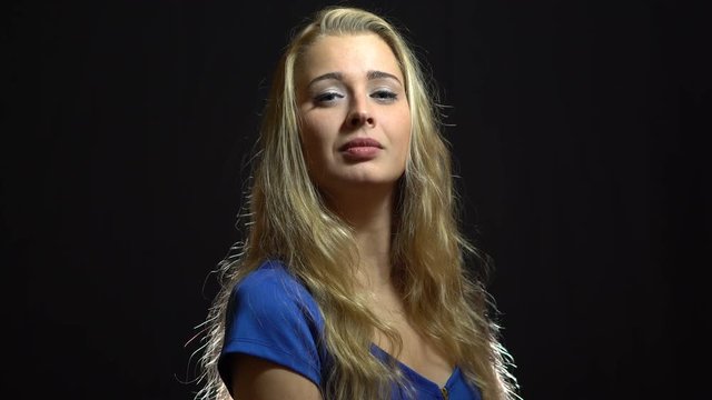 Beautiful Sexy Blonde Girl in Blue Dress looking at you in Studio with Black Background