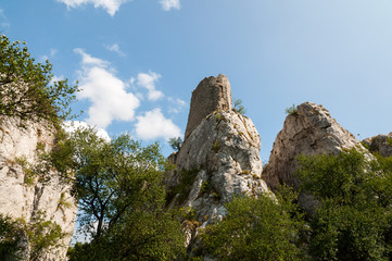 rocks surrounded by a forest with blue sky and white clouds in background