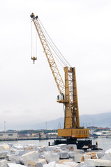 Fototapeta na wymiar Harbor crane and marble stones ready to be shipped