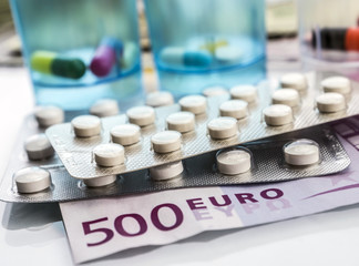 Some blisters of white pills on tickets for 500 euros, conceptual image copaid health
