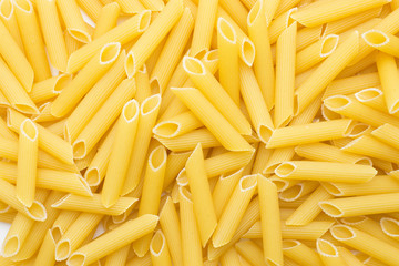 Penne rigate background top view a lot of dry raw pasta pieces.