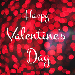 Calligraphy text "Happy Valentine's Day" on red lights bokeh background. Greeting card.