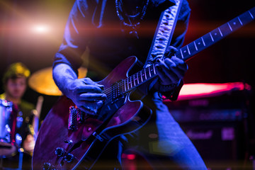 A rocker is playing guitar on stage. - obrazy, fototapety, plakaty