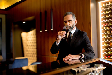 Handsome mature man tasting red wine