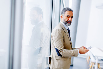 Fototapeta premium Handsome mature businessman with mobile phone in the office