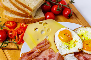 Breakfast fried egg, bread, tomatoes, ham and pepper on wood table