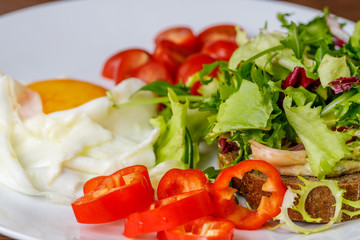 Breakfast fried egg, bread, tomatoes, hummus, pepper and rucola on wood table