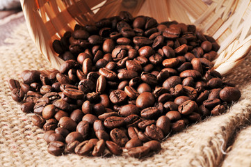 Coffee beans spilled from the basket on a burlap