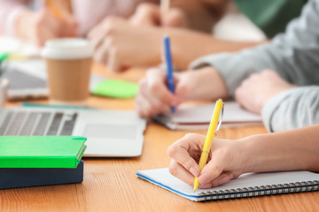 Teenager writing in notebook while sitting at table