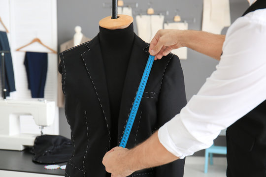 Tailor taking measurements of mannequin in atelier