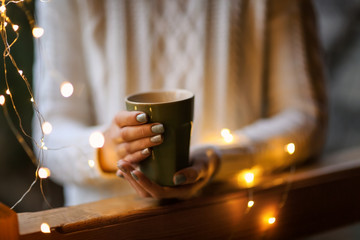 Fototapeta na wymiar Young woman relaxing while drinking tea in living room on winter day