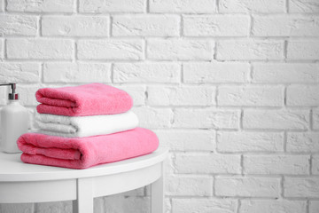 Obraz na płótnie Canvas Stack of clean towels on table near white brick wall