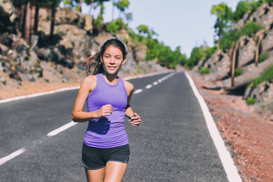 Run exercise fit Asian woman jogging running on mountain road outside in nature. Happy girl exercising wearing purple fashion top sportswear activewear. Fitness and health concept.