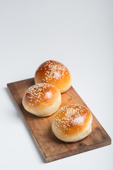 Tasty buns with sesame on oven-tray, on wooden background.