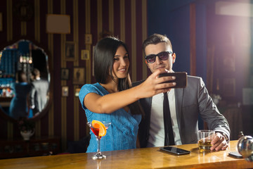 Happy young couple is taking the self-portrait while having fun at the bar