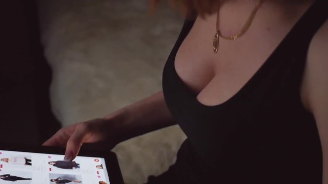 Young woman sitting on the bed and makes online shopping on a tablet. Online shopping concept.