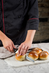 Obraz na płótnie Canvas Cooking bread buns for burger on wooden table by chef hands. White isolated background.