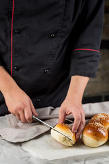 Baker cooking bread buns for burger. Hands preparing bread dough on wooden table. Preparing traditional homemade bread. Hotel service concept.