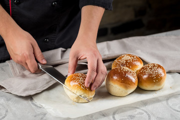 Baker cooking bread buns for burger. Hands preparing bread dough on wooden table. Preparing traditional homemade bread. Hotel service concept.