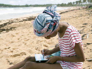 Girl draws watercolor on the beach