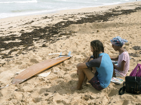 Man Surfer and girl artist on the beach