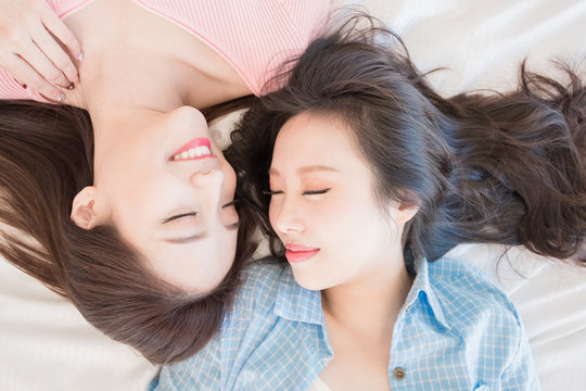 two woman lying on bed