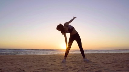 Beautiful woman making yoga in the beach at sunset