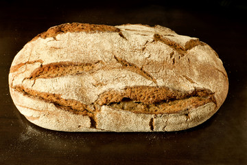 Whole loaf of fresh German sourdough rye bread - high angle view on dark background