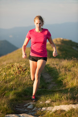 Woman runs on a top of the mountains with mountain range in background