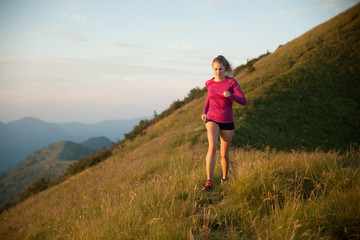 Fototapeta premium Woman runs on a top of the mountains with mountain range in background