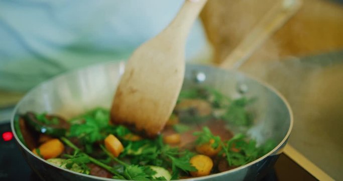 Close up of woman saut&eacute;ing vegetables in pan