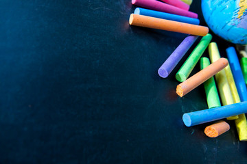 Color of chalk with earth model on chalkboard background. Education concept.