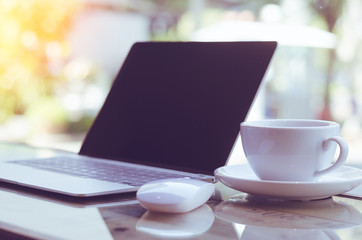empty computer laptop with mouse and coffee cup on table in coffe shop with copy space. freelance concept, still holiday concept, relax working concept.