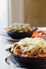 Two chicken salads with cheese and seeds on top,  served in a plastic bowl. 