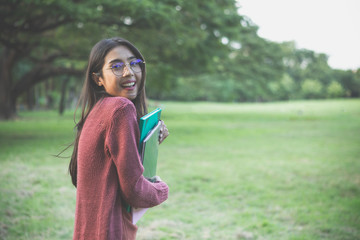 Portrait of high school girl with books in park, education concept