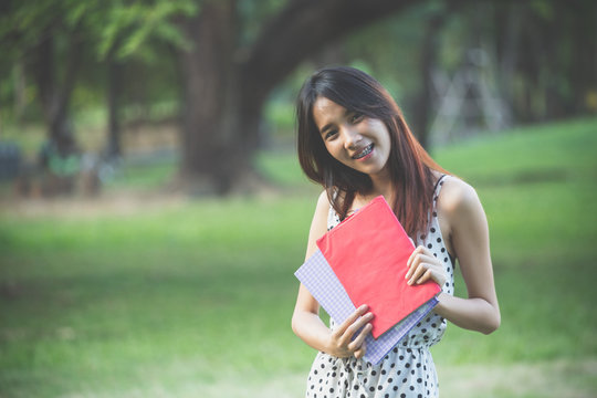 Portrait of high school girl with books in park, education concept