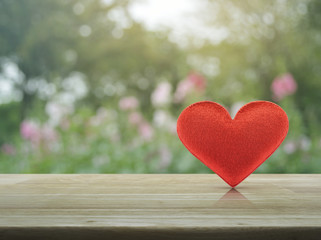 Fabric red love heart shape on wooden table over blur pink flower and tree, Valentines day concept