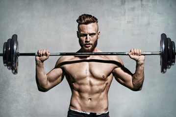 Fototapeta na wymiar Muscular man doing exercise with barbell. Photo of man with perfect body. Strength and motivation