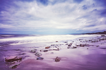 Scenic beach picture, motion blurred water, peaceful natural background, color toning applied.