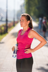 woman drinking water from a bottle after jogging