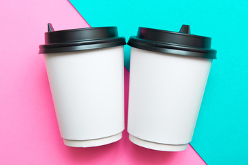 Two disposable cups for hot drinks on a pink and mint geometric backgrounds. Trend colors.