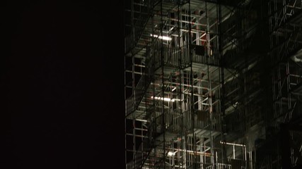 Camera tilts up a high series of scaffolding along a clock tower