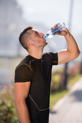 man drinking water from a bottle after jogging