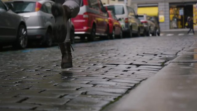 A woman sprints down a paved road in a street in an urban area - slow motion - view from the ground