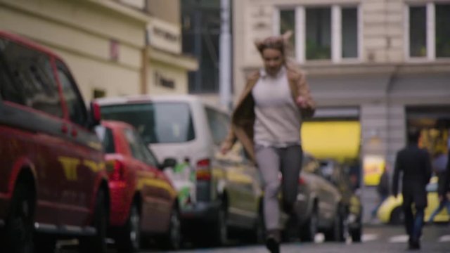 A woman sprints down a paved road in a street in an urban area - slow motion - view from the ground - blurred