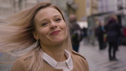 A young beautiful woman tosses her hair and laughs at the camera in a street in an urban area - slow motion - face closeup
